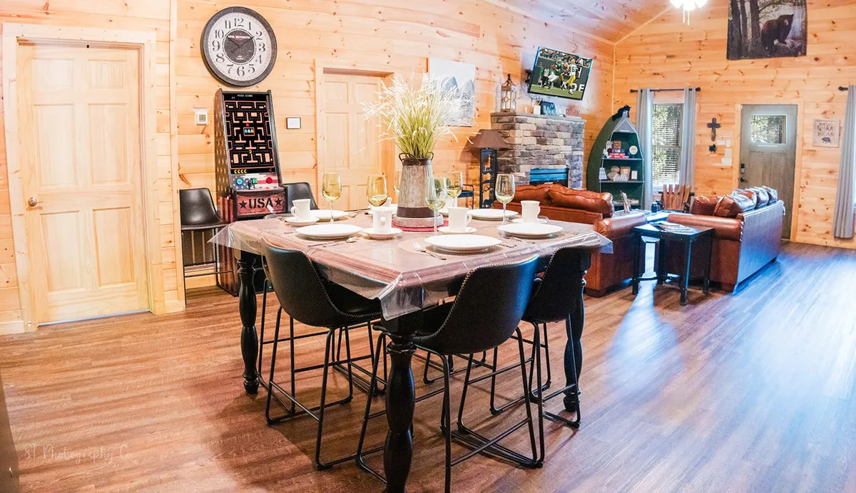 This interior shot provides a harmonious view of a dining table with place settings leading into a welcoming living area complete with a comfortable couch and a fireplace. The arrangement highlights how the spaces flow together for easy access and interaction.