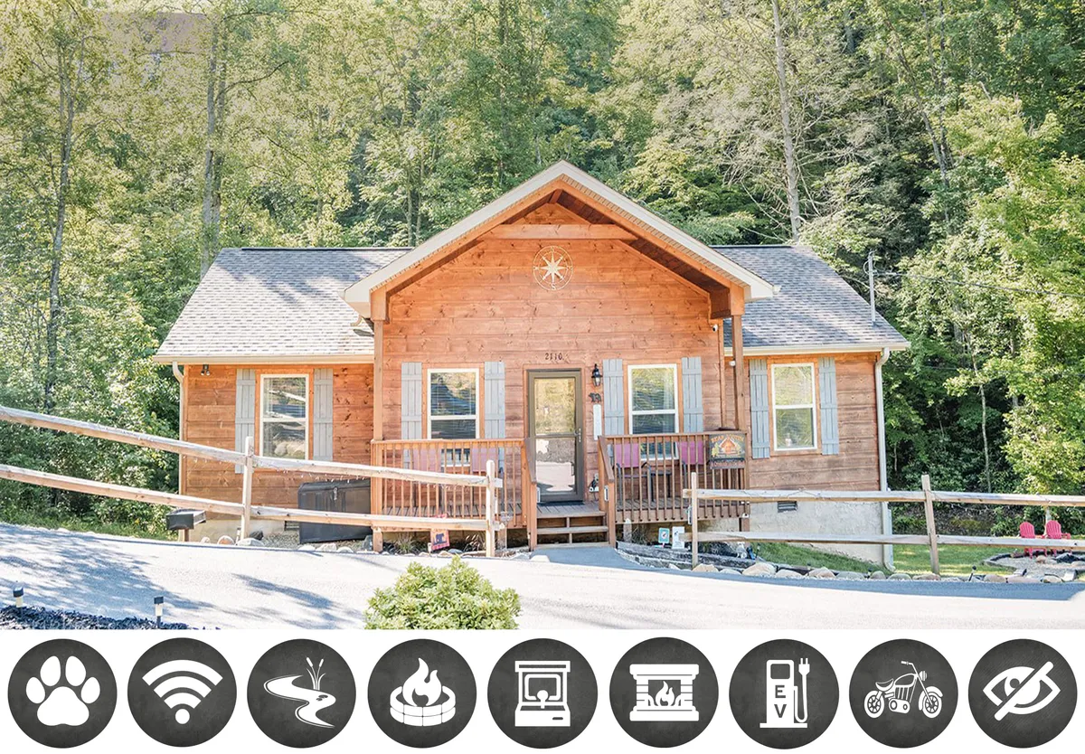 The image showcases the inviting exterior of a charming wooden cabin nestled among trees. The front porch, adorned with a circular star motif and lined with large windows, exudes a warm, welcoming atmosphere. The space is perfect for relaxing outdoors, soaking in sunsets, and gathering with family or friends.